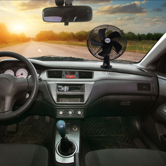 A view of a car interior featuring a dashboard fan, with a road and a sunset in the background, highlighting a comfortable driving experience.
