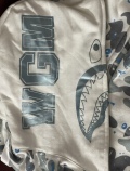 The hoodie looks very good, the quality is very good. The Bape bag, the Bape tag, the bullseye sign, the bullseye sign is also printed on very good, the stitching, the shark face, the WGM (World Gone Mad) is printed on good. Even the white Color is right and the wrist sleeves also have a perfect white color But the most crazy thing about this hoodie is that it even glows when the hoodie is in a dark area like the real one, you only have to put the hoodie in a light area or put the hoodie right under a lamp, so the material that glows can charge up on light. This feature is just so crazy. I would also consider sizing up if you want a more baggy look and if you want to zip up your hoodie completely to the top. Overall the hoodie is very good and PkStockX is a very customer friendly company and I can only recommend them, their work is just insane. I will also buy again from here in the future. Thank you so much PkStockX.
