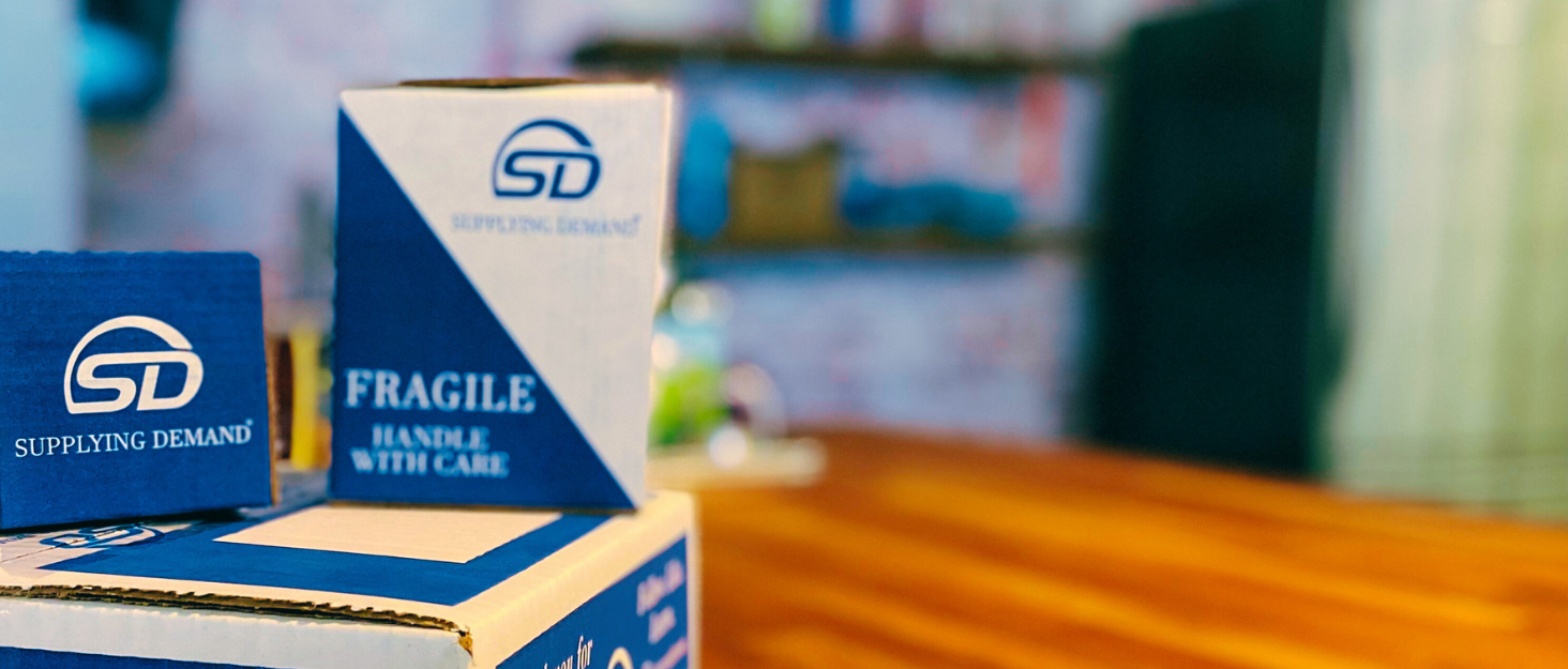Supplying Demand boxes sit atop a butcher block countertop.