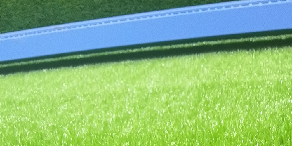 Why does football artificial grass perform better than real grass in use