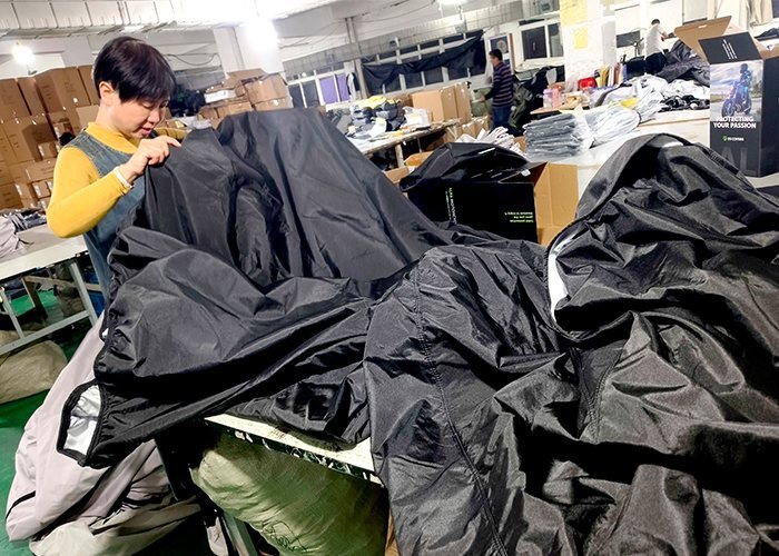 Factory worker inspecting a finished motorcycle cover before packing