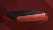 A sleek black and red desktop device featuring multiple USB ports, positioned on a circular surface with a smooth, minimalist design.